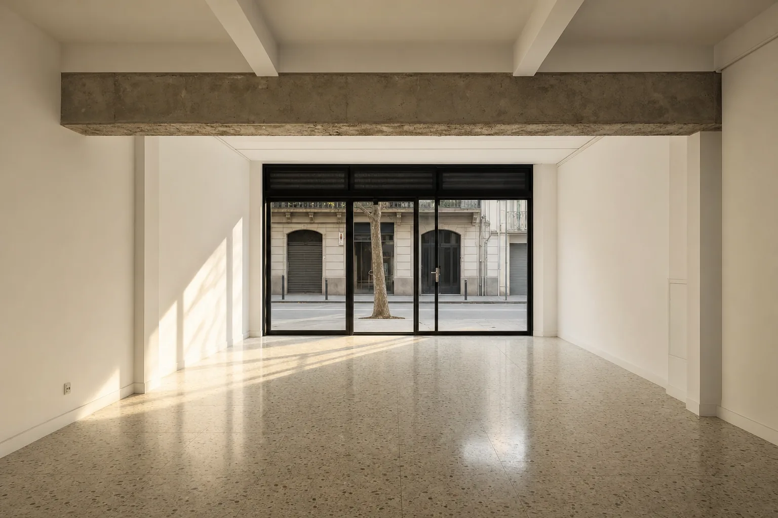 Local comercial de Barcelona completamente vacío y barrido al final del trabajo, con el suelo de terrazo reflejando la luz de la tarde