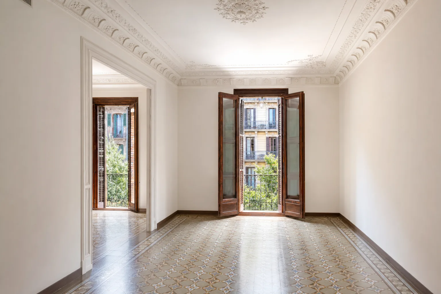 Sala del Eixample recién reparada y pintada, con la moldura restaurada y las puertas de balcón abiertas a la luz de la tarde