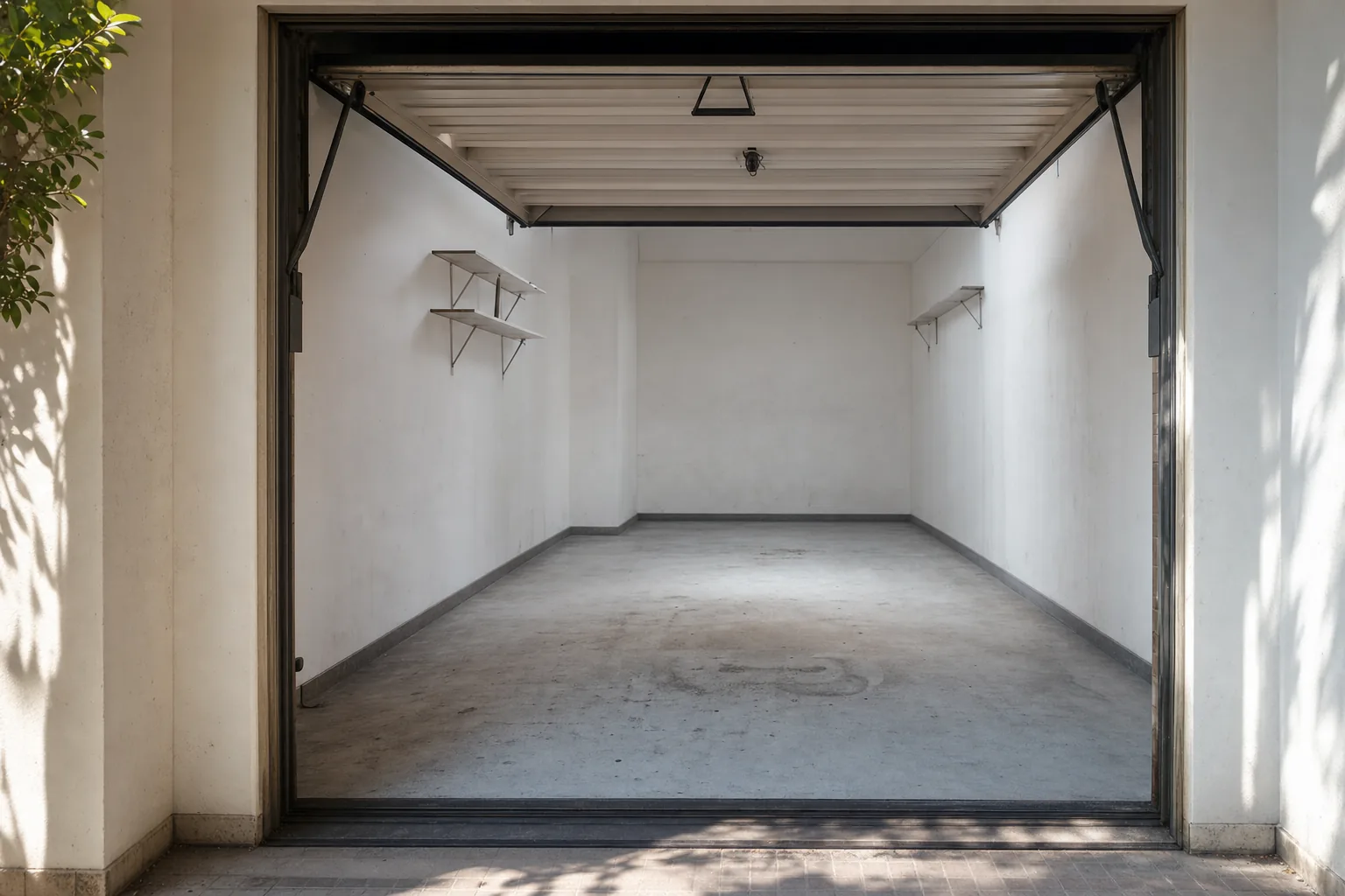 Plaza de garaje de una finca de Barcelona completamente vaciada, con el suelo barrido y la puerta basculante abierta a la luz