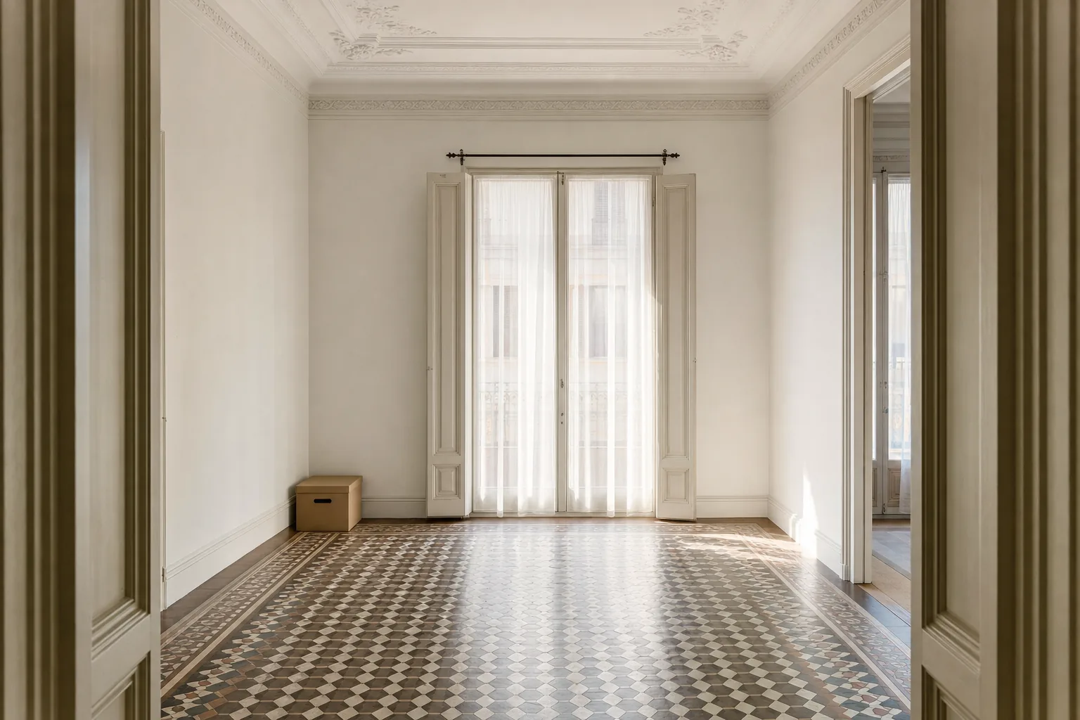 Piso del Eixample vacío y limpio tras el vaciado, con luz suave de la mañana y una caja de archivo junto a la puerta con lo que la familia conserva